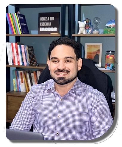 foto do raphael salgado sentado, sorrindo, com uma estante atrás